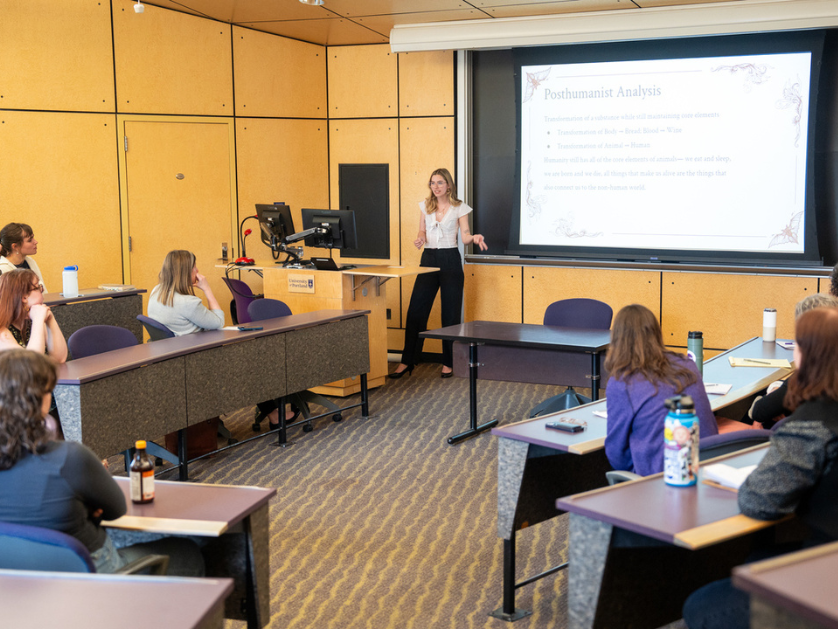 A professor delivers a lecture to students in a large classroom.